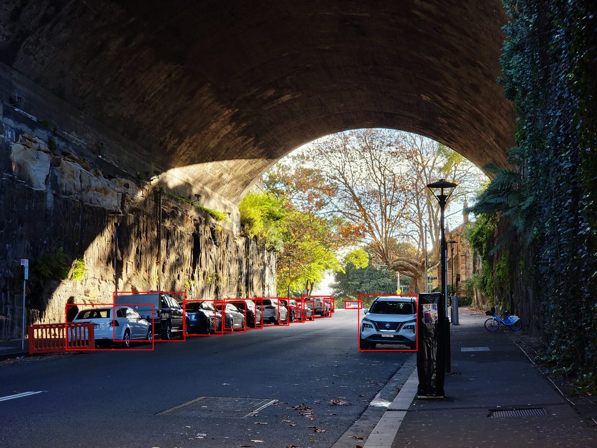 Street scene under a stone bridge with twelve parked and moving cars each outlined by a red bounding box labelled car